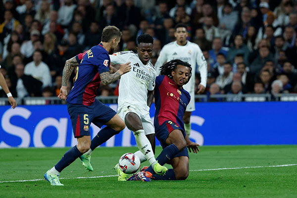 Vinicius Jr, delantero del Real Madrid, siendo marcado por dos jugadores del Barcelona . Foto EFE